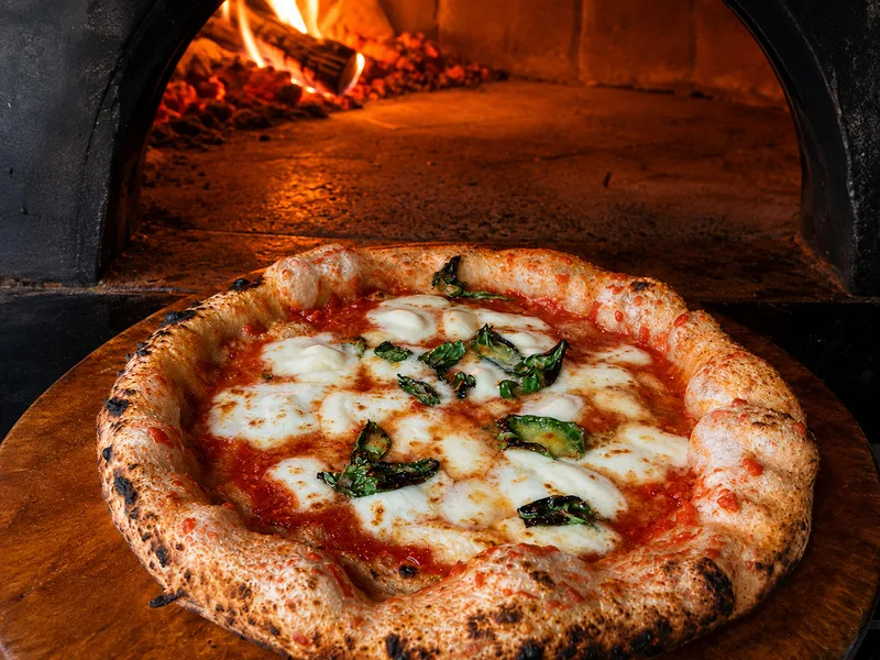 Pizza Napoletana nổi bật với đế bánh mỏng, viền mềm, cà chua, mozzarella và húng quế.